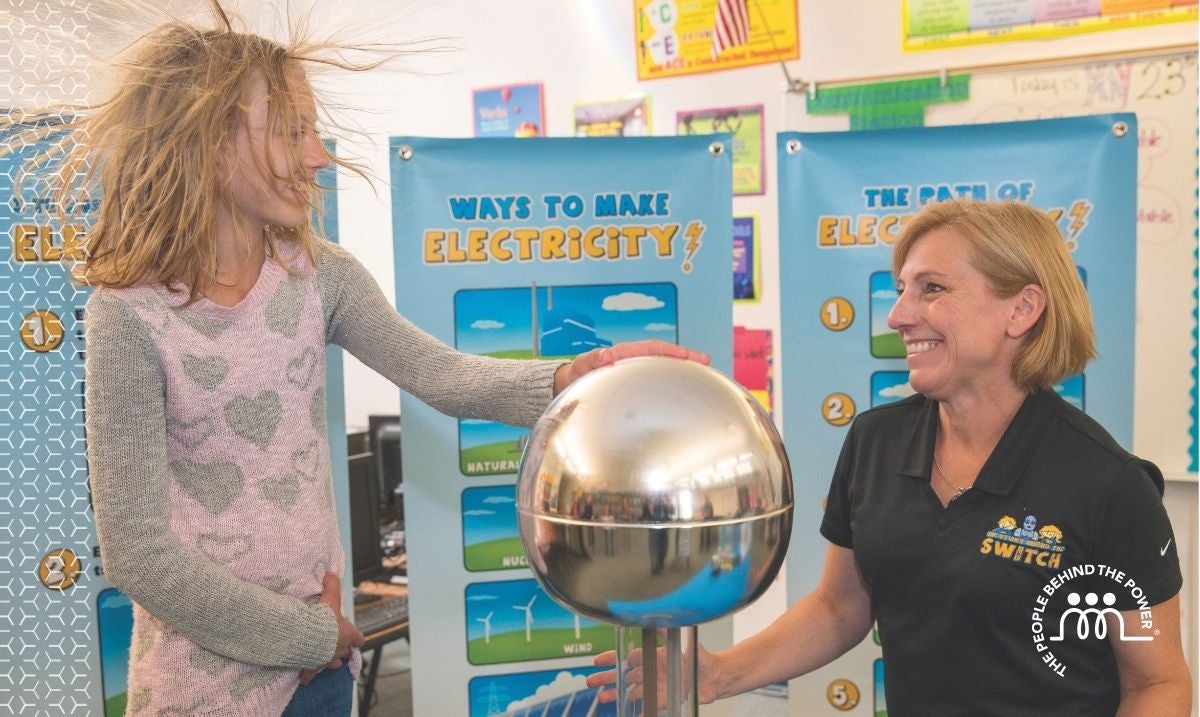 Michelle Pastor on right and girl touching a Van de Graff and her hair sticking up from the electricity