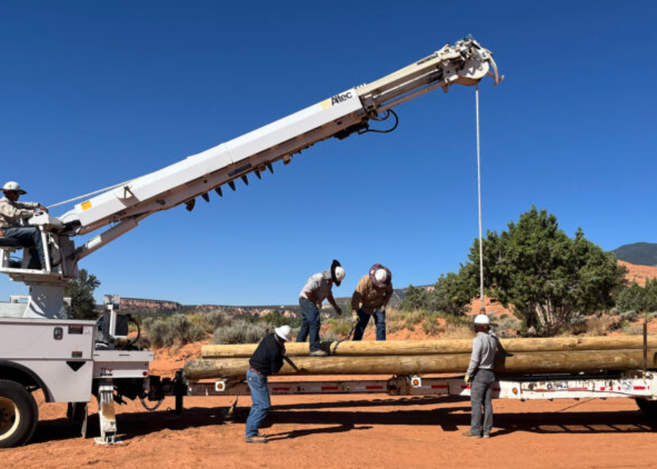 Tri-State member Mountain View Electric Association (MVEA) lineworkers hauling logs onto truck with crane to bring power to one family